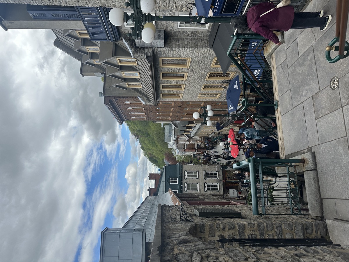 A street view in Quebec with stone buildings and cloudy sky.